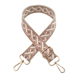 Close-up of jacquard embroidery strap with golden metal hooks and geometric pattern