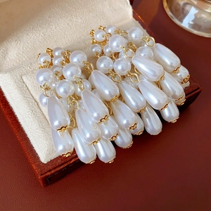Detailed view of white teardrop pearl tassel earrings in a red jewelry box