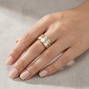 Dettaglio di un anello a tre strati con finitura dorata, fascia in smalto bianco e cristalli
