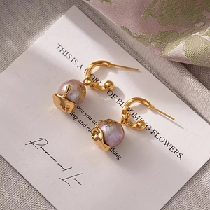 Elegant gold hoop earrings with light purple pearls and gold leaf accents on a white card