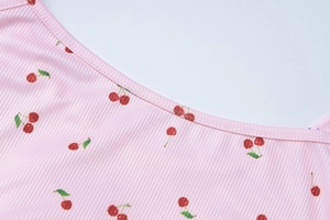 Détail d'une robe rose à motif cerise avec texture côtelée sur le décolleté