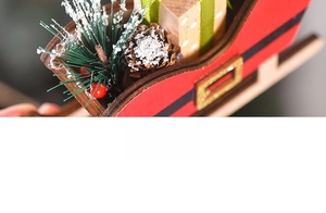 Detail of wooden Christmas sleigh with pine branches, berries and gift box decor