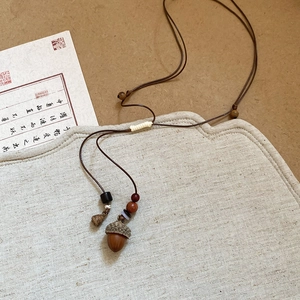 Detail of Zen style acorn pendant necklace with wooden beads and woven rope