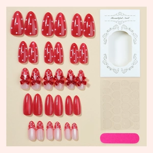 Red almond press-on nail set with white polka dots, glitters, and bow details in box
