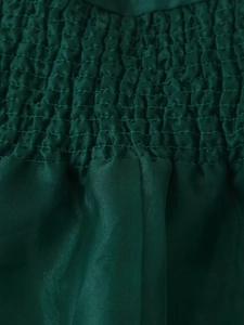 Nahaufnahme der dunkelgrünen gesmokten Stofftextur mit elegantem Satinglanz und Raffungen