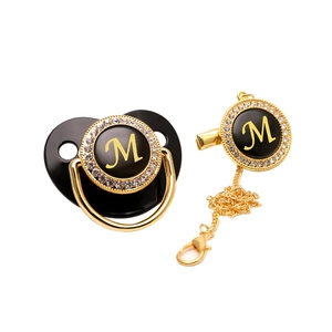 Luxurious black baby pacifier with gold rhinestones and capital letter M detail