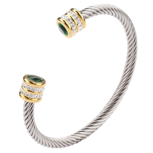 Macro detail of twisted stainless steel cuff bracelet with green gemstones and pavé stones