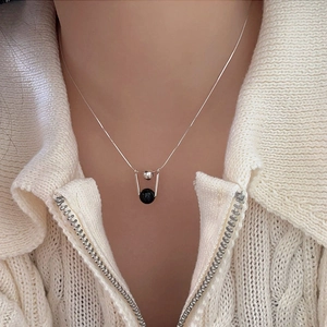Close-up of a minimalist 925 silver necklace with black agate pendant on a model