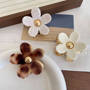 Close-up of elegant acetate flower hair claws in pearl white and tortoiseshell on a tray
