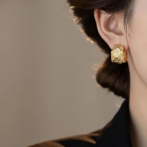 Retro golden C-shape earrings with textured metal finish worn by a fashion model
