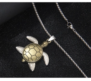 Detail of vintage turtle pendant with gold shell and silver limbs on black background
