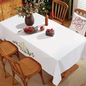Detail of white Christmas tablecloth with gold and green snowflake leaf embroidery