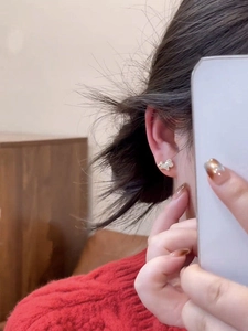Close-up of sparkling horse stud earring with gold plating and white zircon on ear