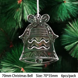 Close-up of clear acrylic Christmas bell ornaments with ribbon on green pine branches