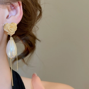 Detail of gold rose earrings featuring water drop pearls and long chain tassels for women