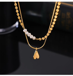 Gros plan sur un collier double rang doré avec perles blanches et pendentif coeur