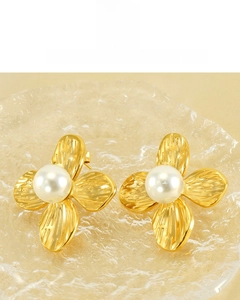 Detail of 18K gold plated petal earrings with pearl center on glass plate