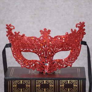 Macro detail of red sequin glitter lace party mask with black ribbon ties on vintage book