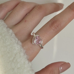 Hand model wearing a silver ring with a pink heart-shaped gemstone and small clear stone