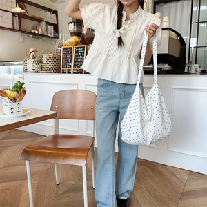 Detailed view of large polka dot canvas tote bag shown in a cozy cafe setting