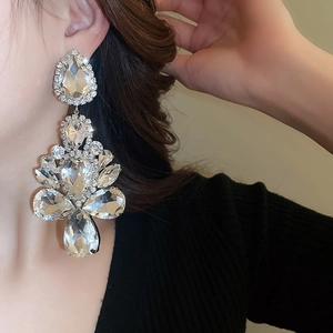 Detailed view of model wearing large sparkling rhinestone waterdrop earrings with alloy base