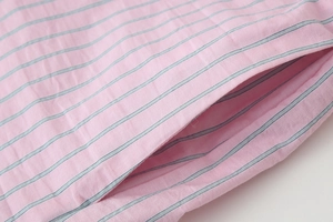 Détail d'un short en coton rayé rose et bleu avec une poche latérale bien finie