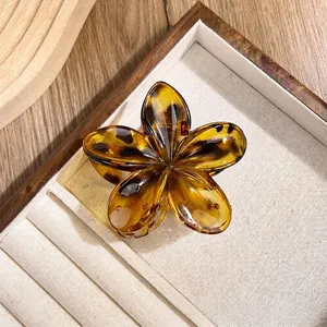 Detailed view of amber tortoise shell flower hair claw clip on a wooden display tray