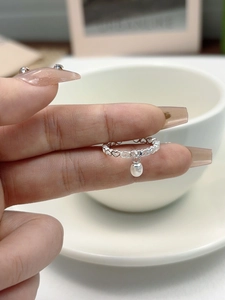 Detail of s925 silver hollow heart chain ring featuring a dangling freshwater pearl charm