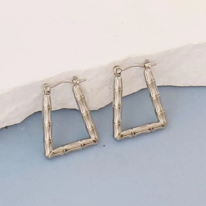 Detail showing irregular geometric silver earrings with bamboo texture on a white stone