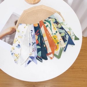 Various vintage floral printed silk scarves and long hair ribbons neatly displayed on a tray