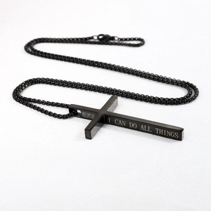 Close-up of black cross necklace with Philippians quote engraving on the side