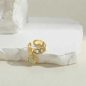 Gold chain ring featuring a zircon evil eye flower charm on a white stone background