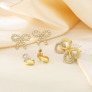 Detailed view of 18K gold-plated bow and heart earrings with pearls on silk background