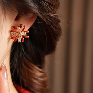 Macro detail of red enamel flower earring with zircon inlay on model's ear