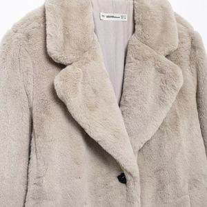Front view of thick faux fur coat in beige featuring lapel collar and black button detail