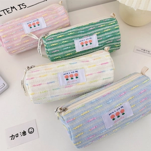Detalle de estuches de tweed texturizados con cremallera, asa y etiqueta con flores
