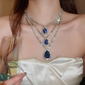 Dettaglio della collana a tre strati con pendenti a goccia blu scintillanti su una modella