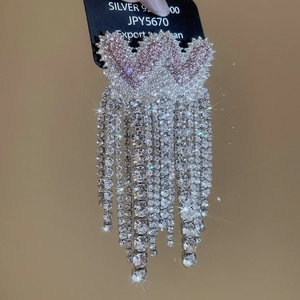 Macro shot of silver tassel earrings with heart motifs and sparkling rhinestone fringe