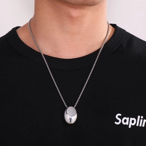 Close-up of polished silver teardrop pendant necklace worn by model on black t-shirt