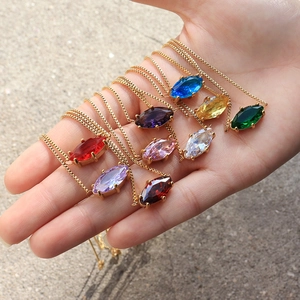 Colorful marquise cut gemstone necklaces on gold chain held in palm for a vibrant look