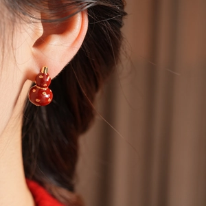 Detailed view of red gourd earring with gold dots on a model in vintage style