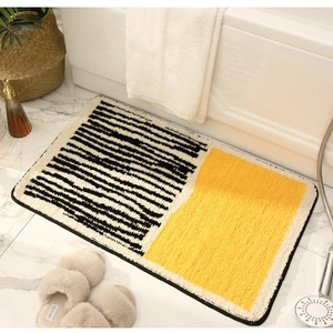 Detailed plush bathroom mat with yellow and black stripes next to a white bathtub