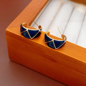 Macro detail of gold vintage C-shaped hoop earrings with blue enamel and geometric patterns