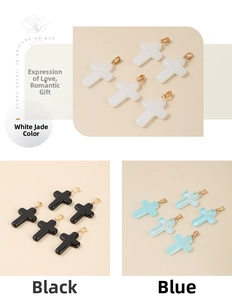 Detailed view of glass cross pendants in white, black, and blue with gold bails