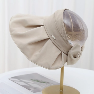 Detail of beige sun visor showing side metal logo and rear bowknot decoration
