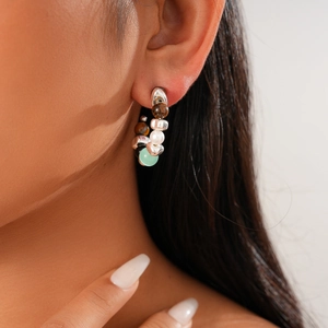 Detail of beaded hoop earrings with tiger eye, turquoise and faux pearls on a model