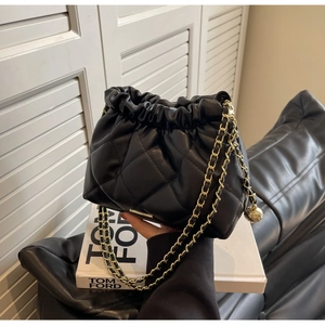 Close-up of black quilted bucket bag with golden chain and drawstring closure details