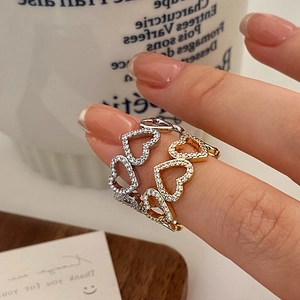 Hollow heart rings with zircon pave in silver and gold tones on a model's hand