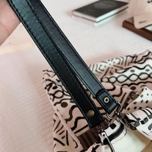 Close-up of black leather shoulder strap with silver metal swivel hook on canvas tote