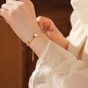 Vue détaillée du bracelet en perles plaqué or sur le poignet d'un mannequin sous un éclairage doux